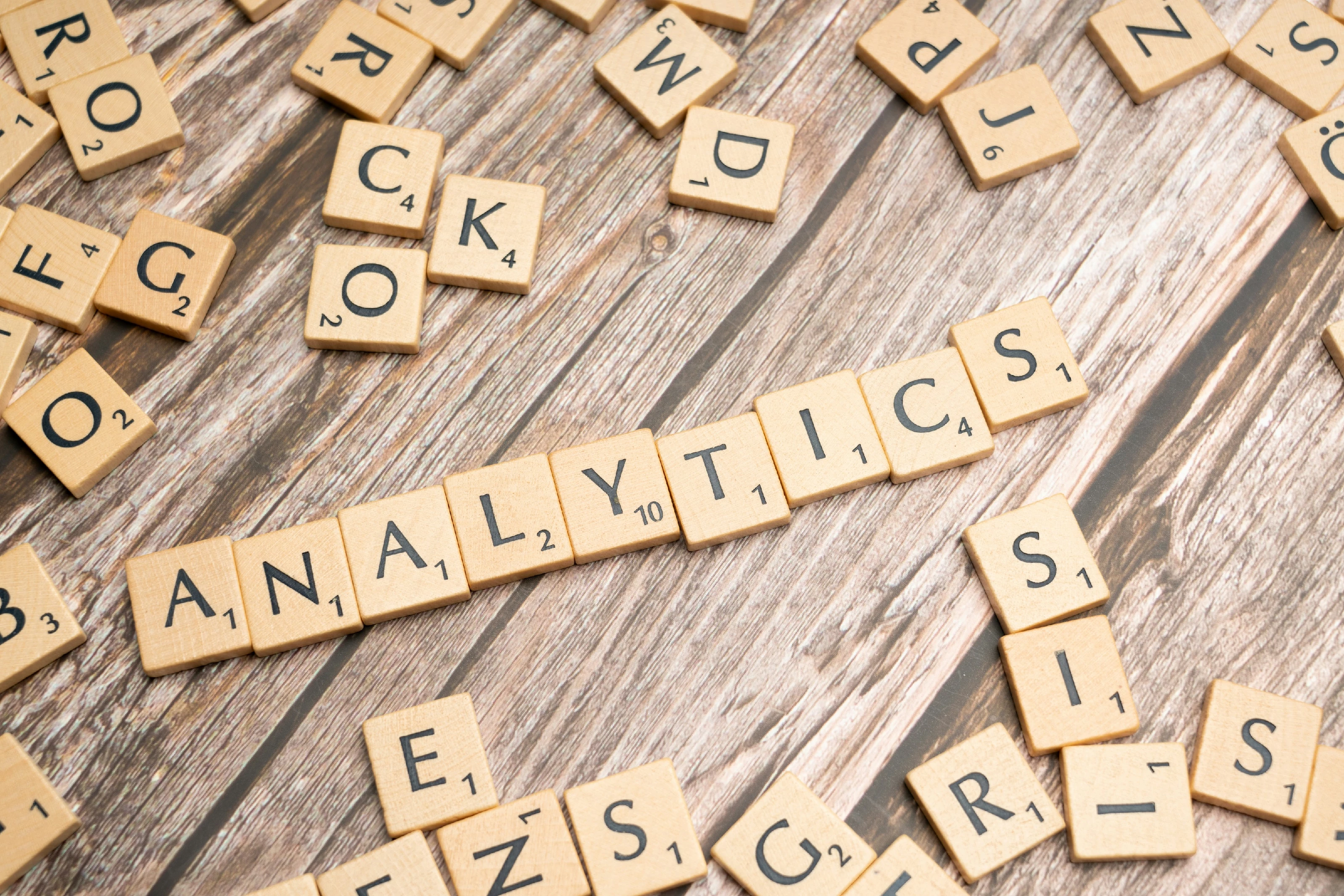 Photo of letter tiles spelling analytics on a wooden table, used as a visual metaphor for marketing analytics and evaluation.